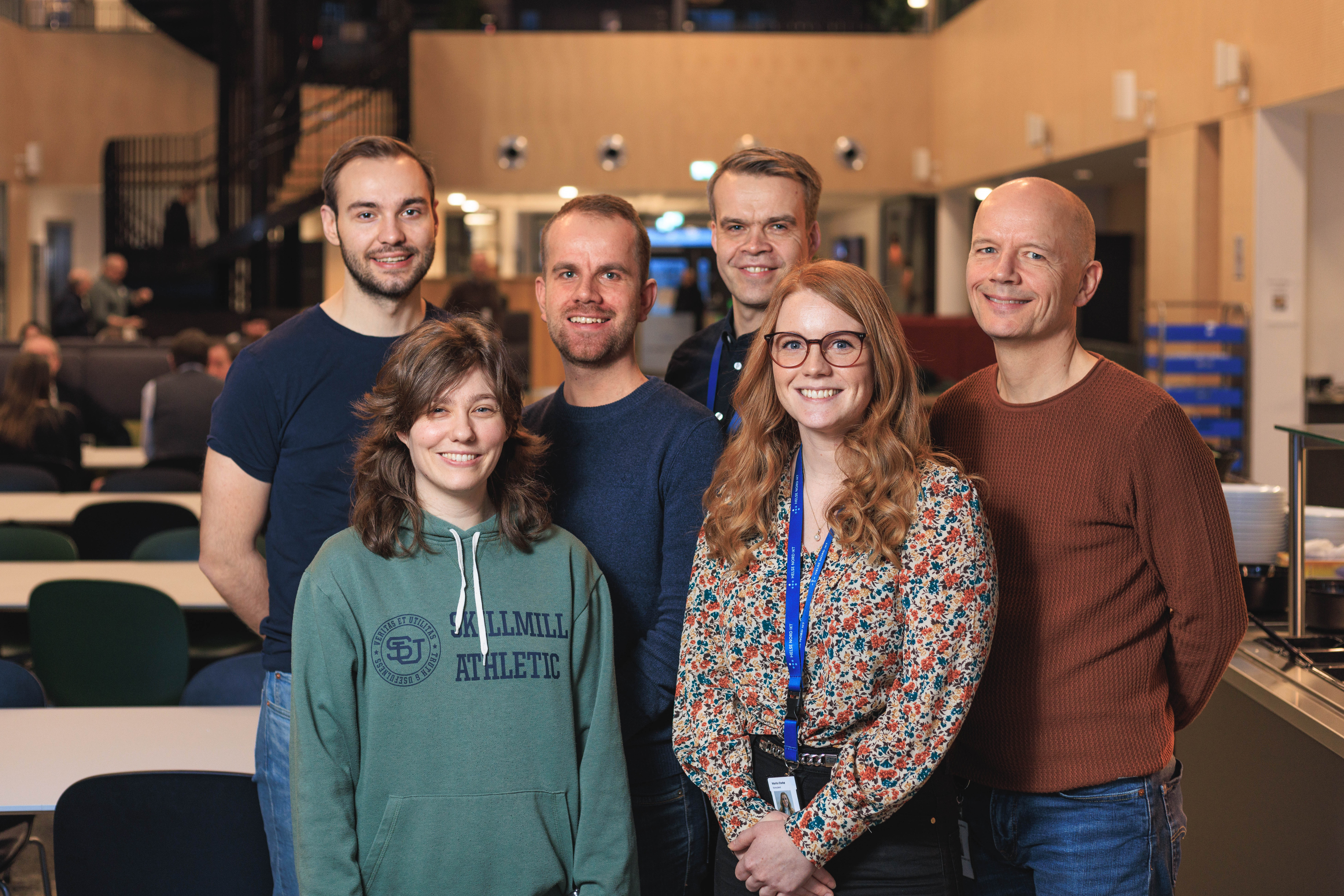 Seks medarbeidere i Helse Nord IKT som smiler til kamera.