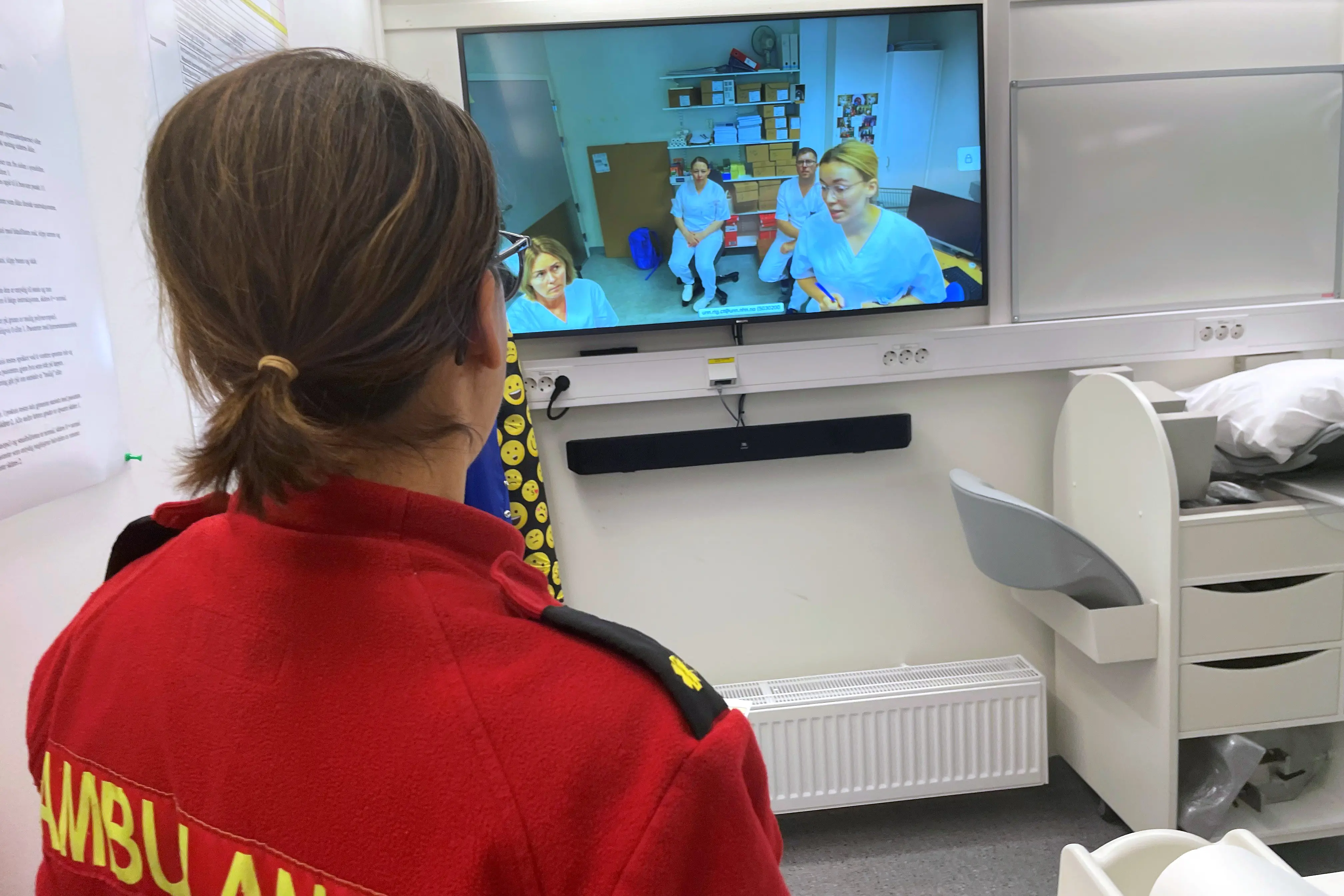 Ambulansearbeider Emilia Agersborg konfererer med teamet i Tromsø. Nevrolog Birgitte Falck nede til høyre på skjermen.