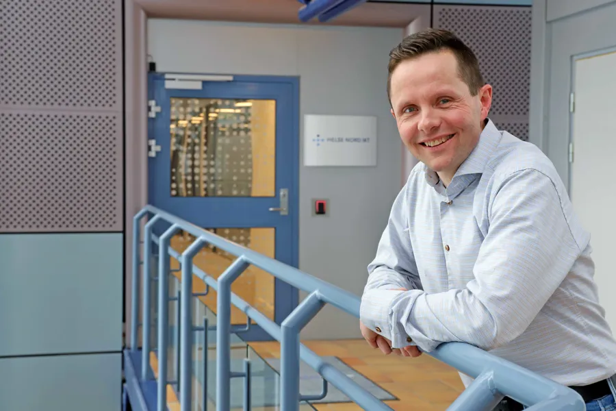 Prosjektleder Bjørn Even Schulz lener seg mot et rekkverk og ser smilende i kamera.