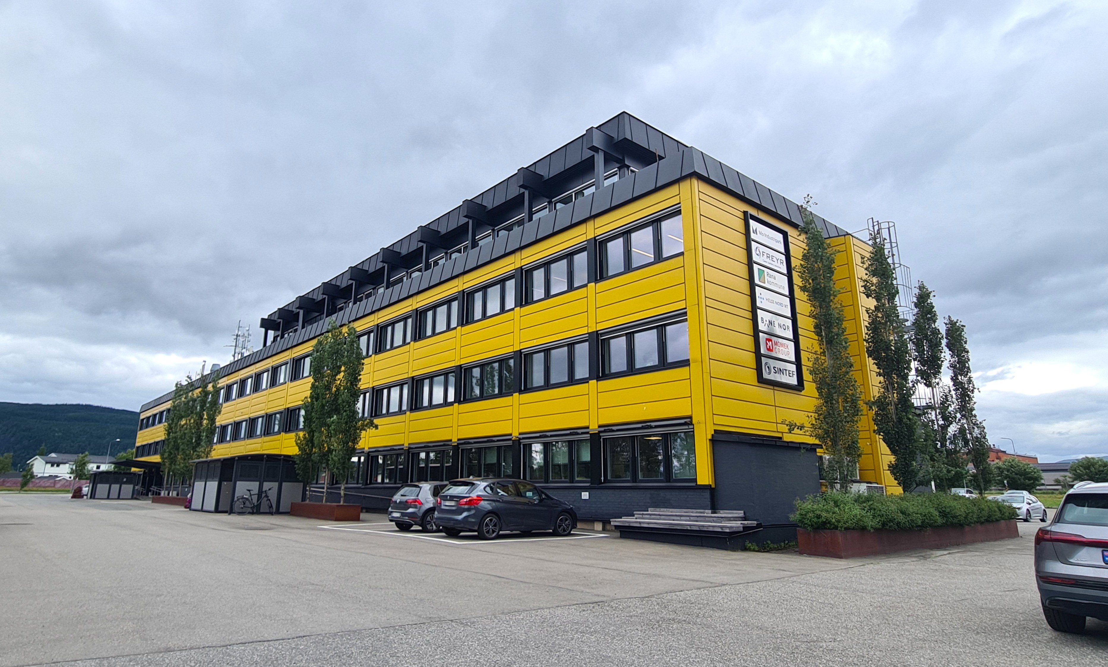 En gul bygning med trær i front