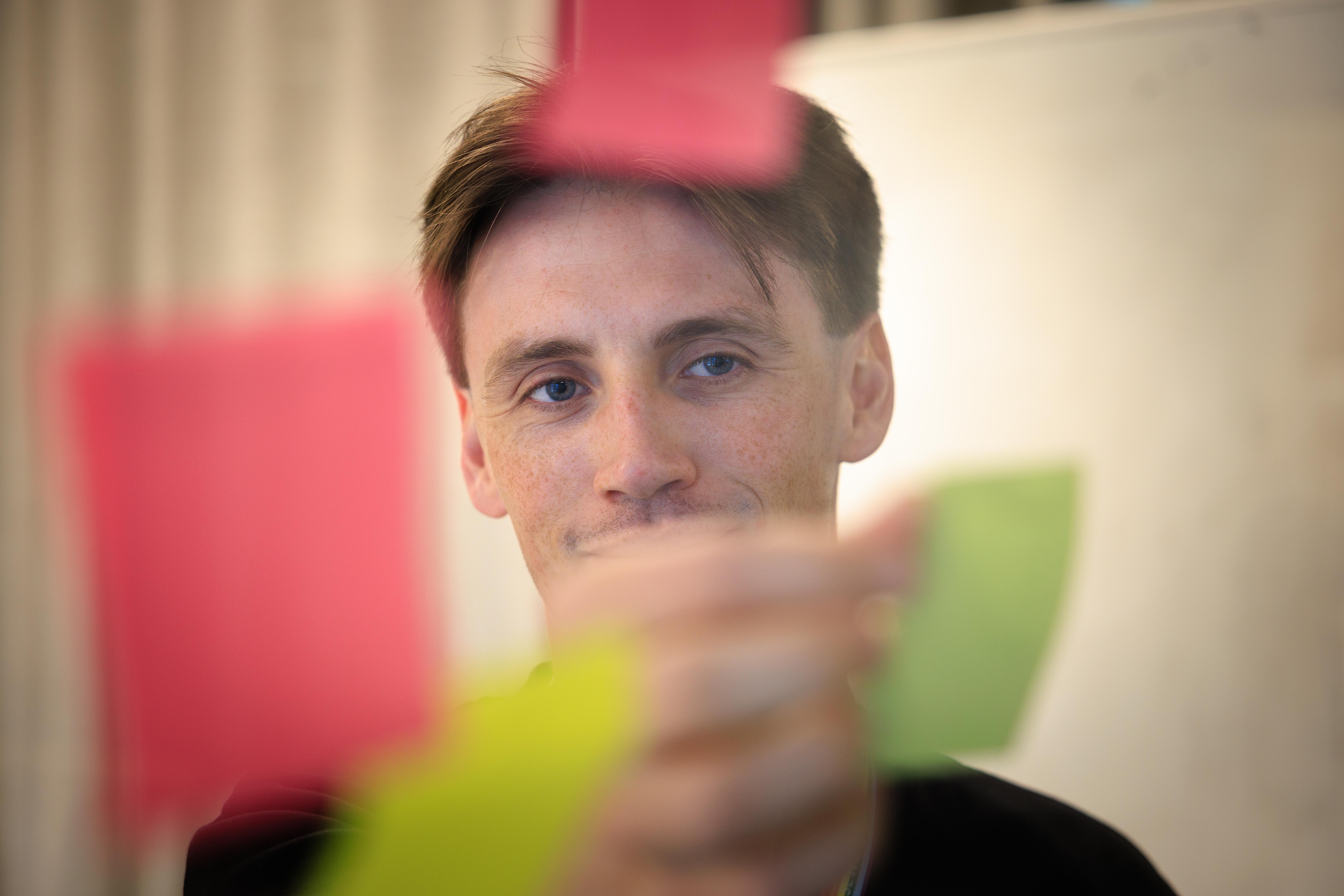 En mann med som holder post-it lapp.