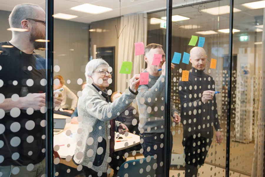 Kolleger som jobber med post-it på en glassflate.