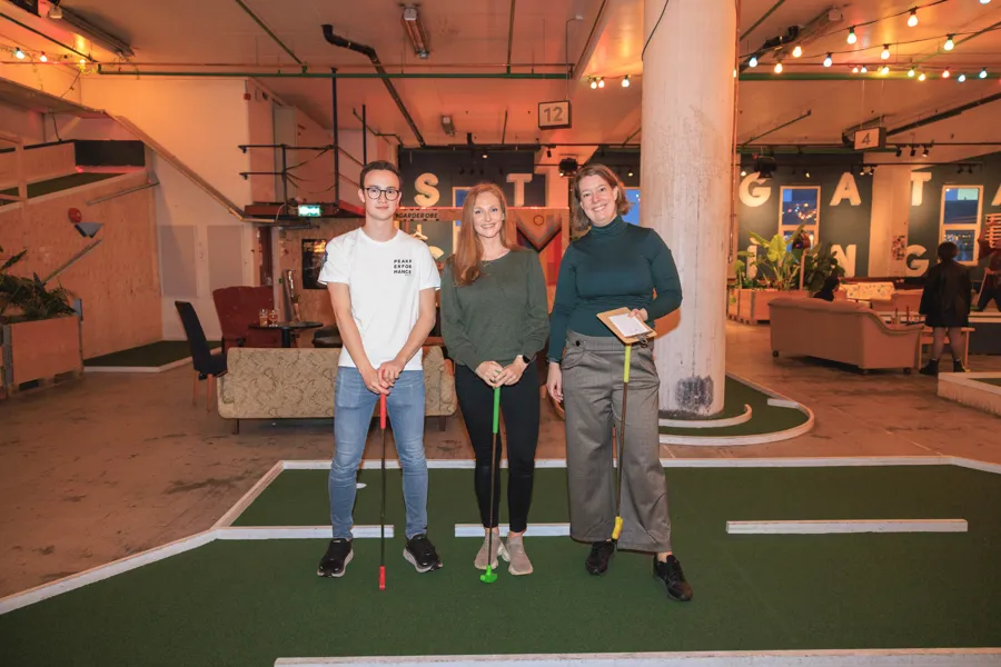 Tre ansatte på minigolf med hver sin golfkølle.