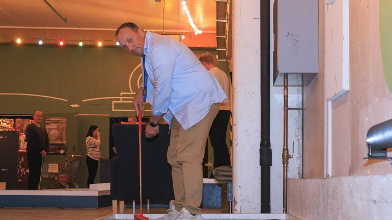 Enn mann som slår et minigolf-slag.
